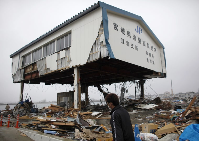 Image: A fisherman walks in a fishing port at an area that was devastated by the March 11 earthquake and tsunami, in Watari